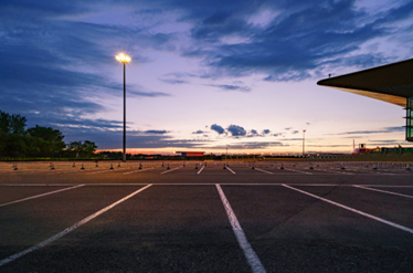 an empty parking lot lit by a commercial light pole at dusk