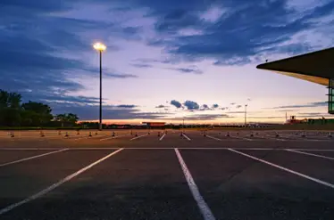an empty parking lot lit by a commercial light pole at dusk