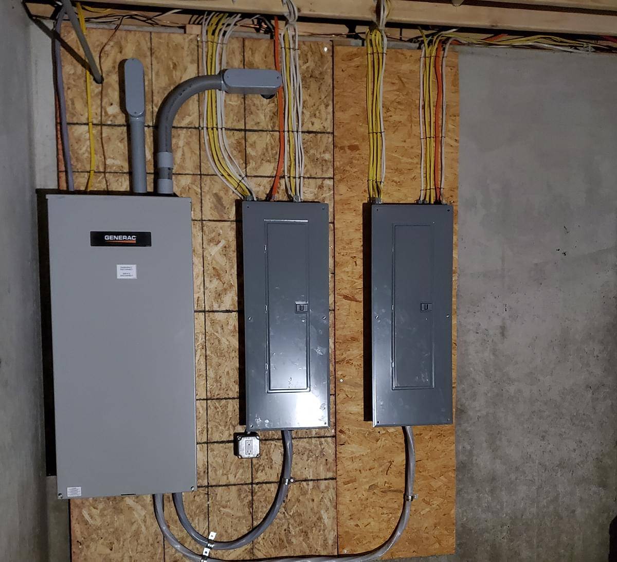 a newly installed generac generator panel next to two electric panels